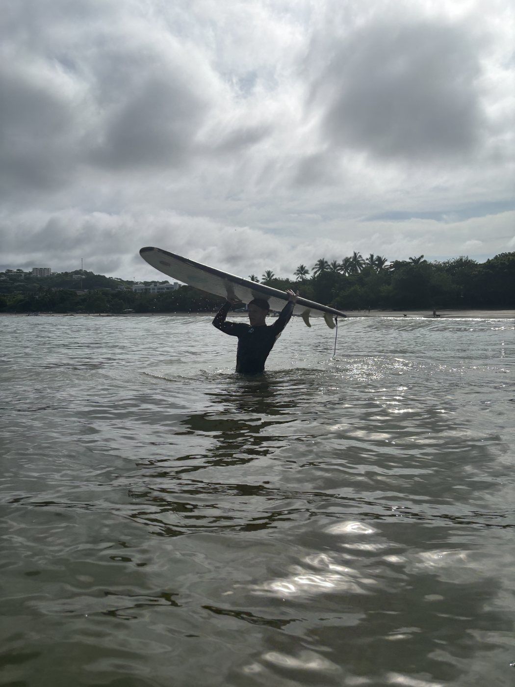 Taras saliendo del agua con una tabla de surf sobre la cabeza