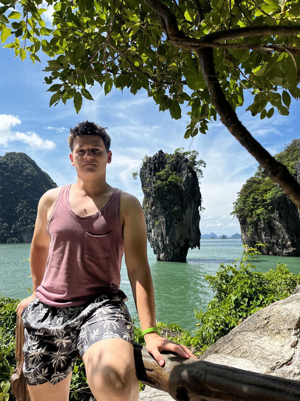 Taras sentado en las rocas con los islotes de la bahía de Phang Nga detrás